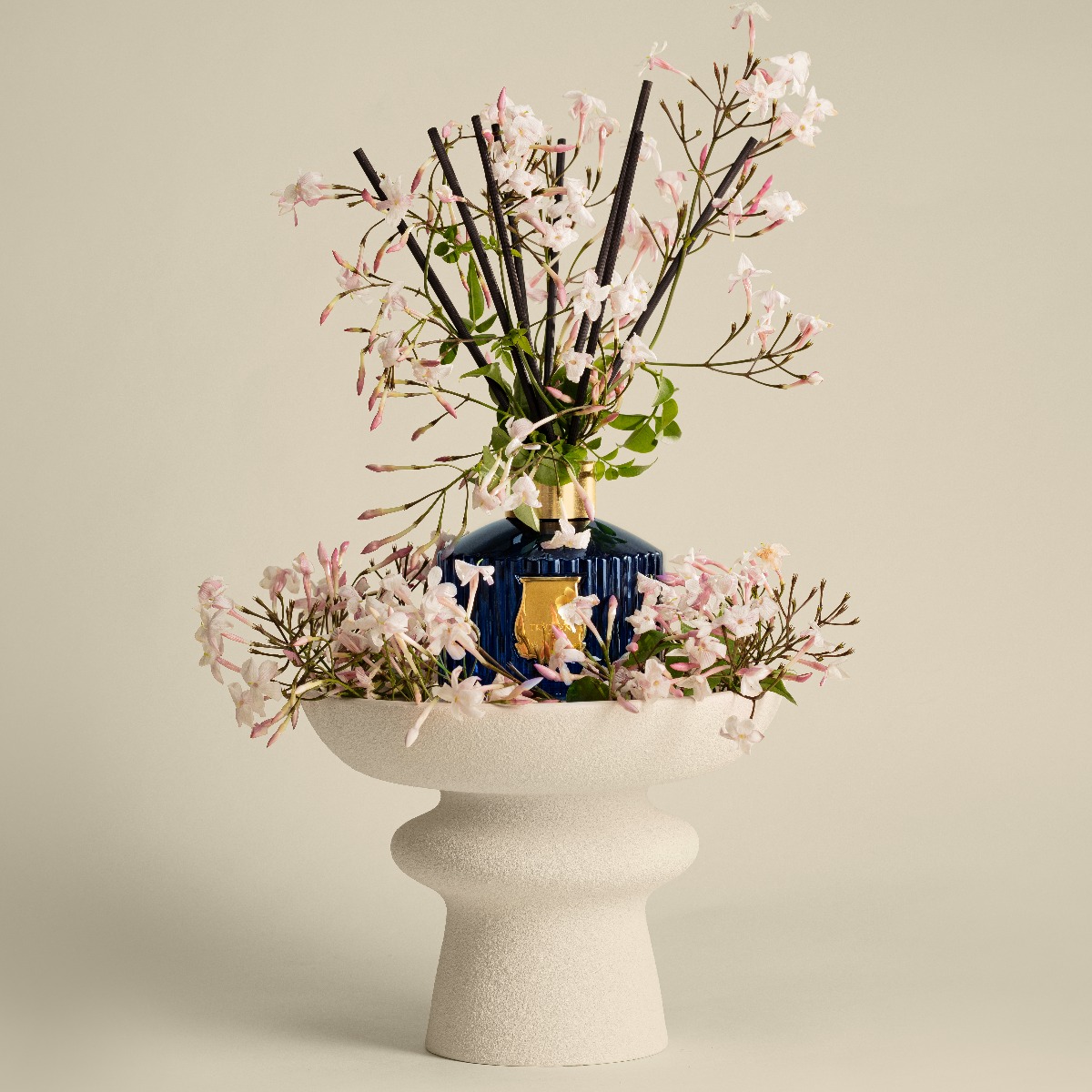 Trudon diffuseur Maduraï lifestyle, posé sur un vase, entouré de jasmin.